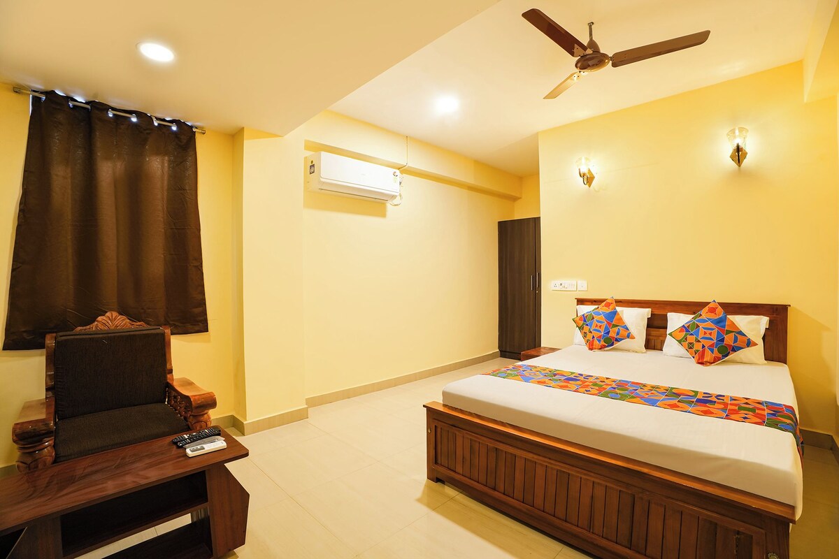 A bedroom with a bed, a desk, a chair, a ceiling fan, and an air conditioning unit.