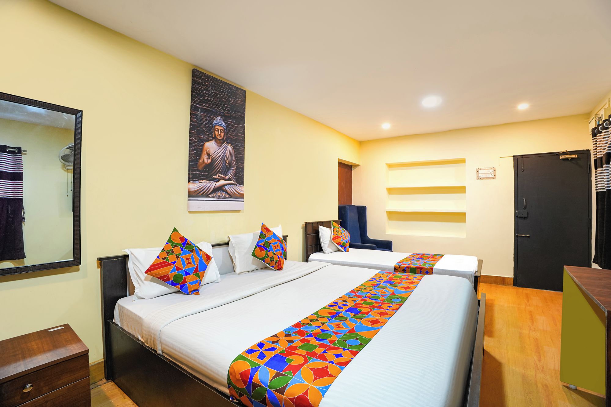 Habitación de hotel con dos camas, un espejo grande, un cuadro en la pared y un armario.