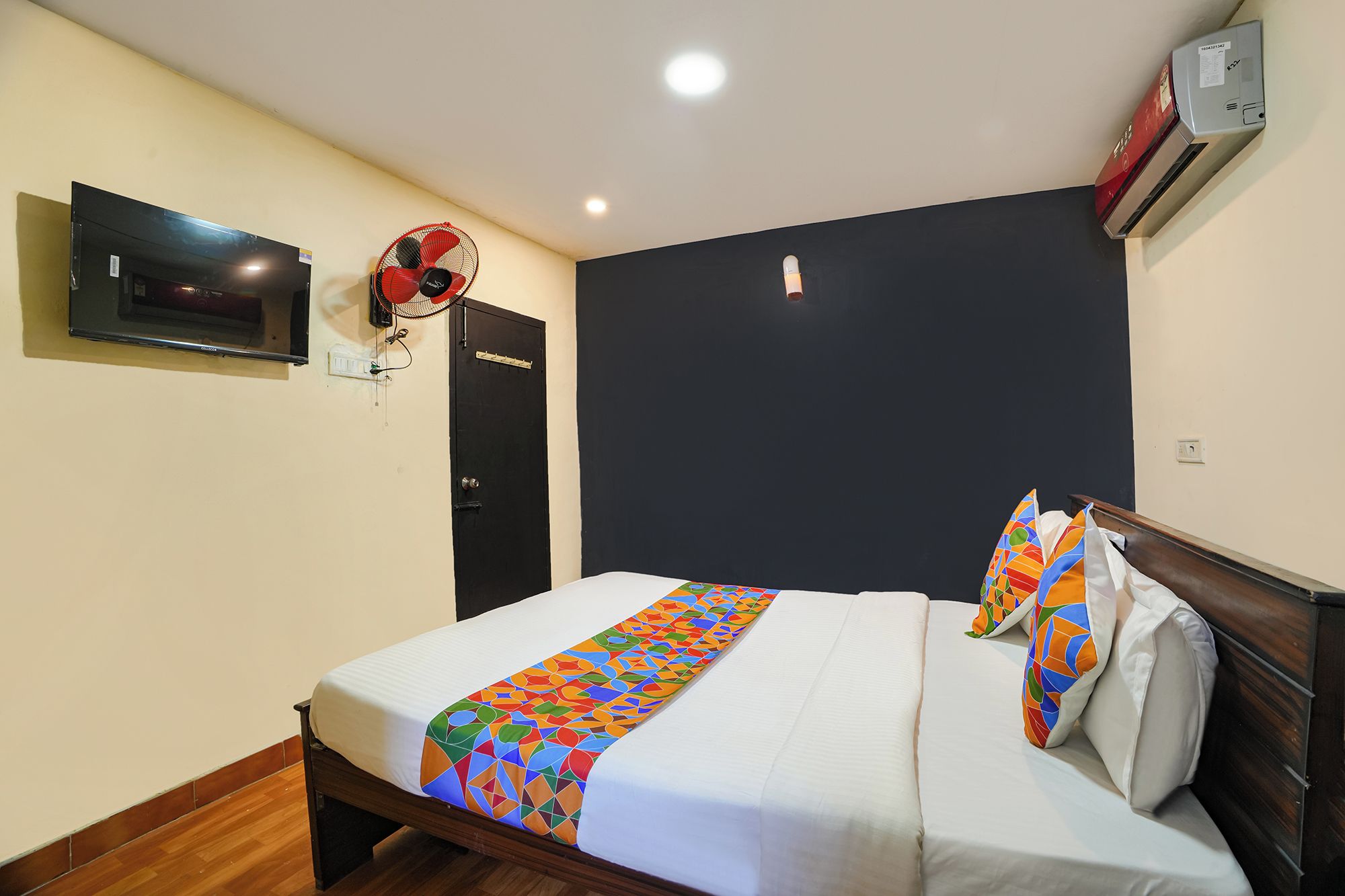 Une chambre d’hôtel équipée d’un lit, d’une télévision, d’un climatiseur fixé au mur et d’une porte.