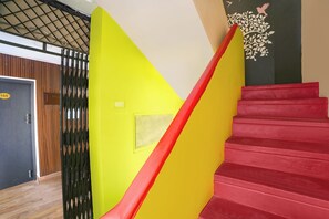 A staircase with a red handrail and a yellow wall. - FabHotel India Gate Par View (Chennai)