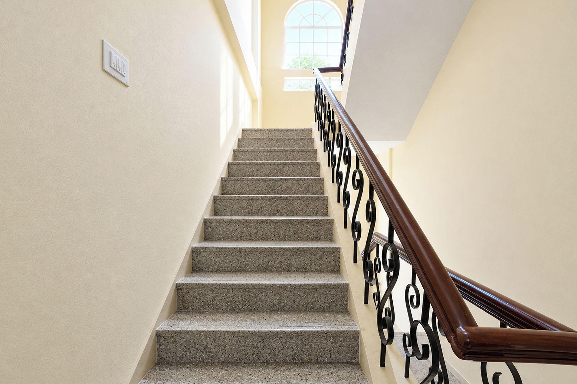 Una escalera con barandilla de madera y pared de color claro.
