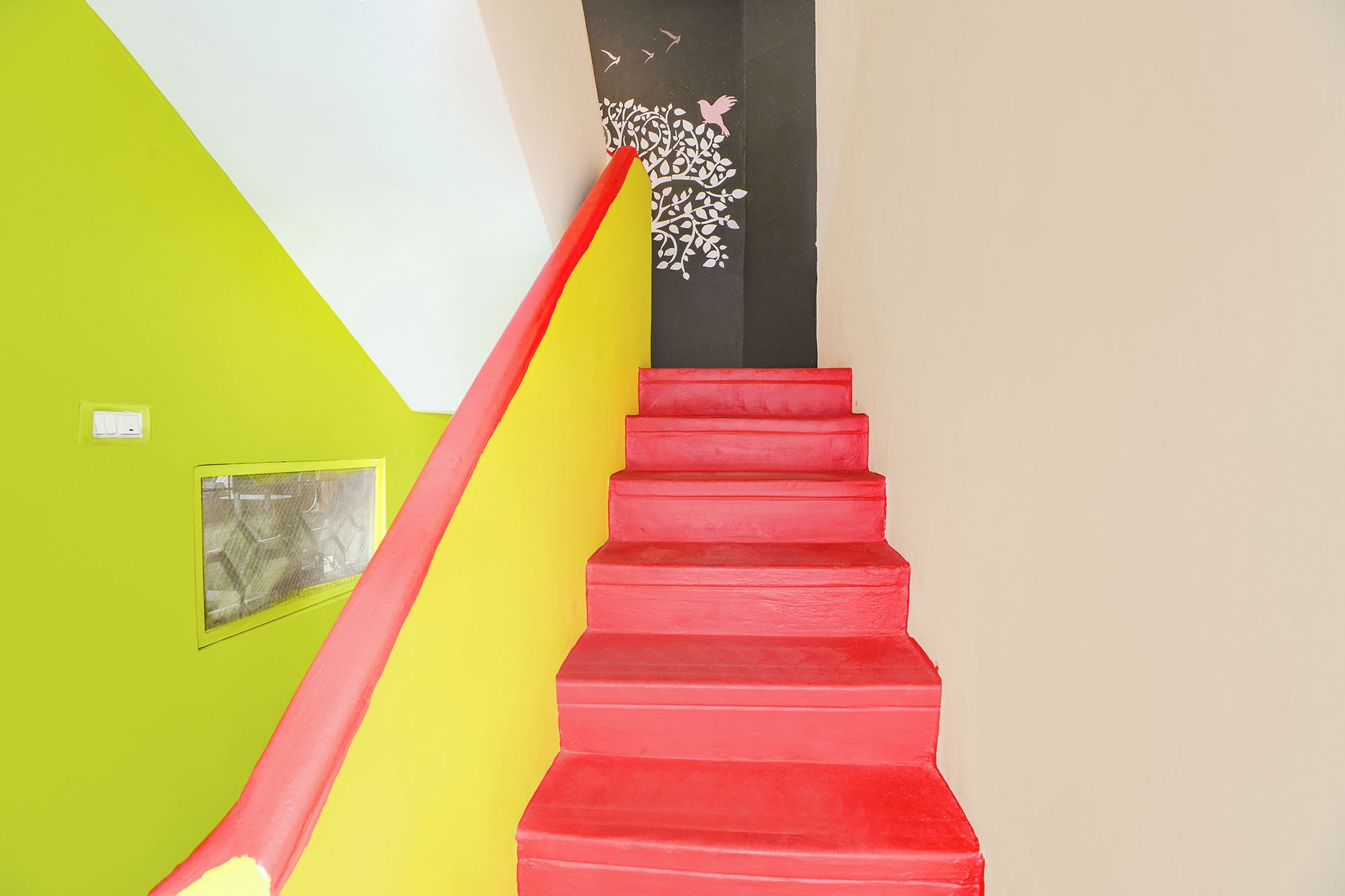 Una escalera con peldaños rojos que conduce a una pared negra con siluetas de pájaros blancos.