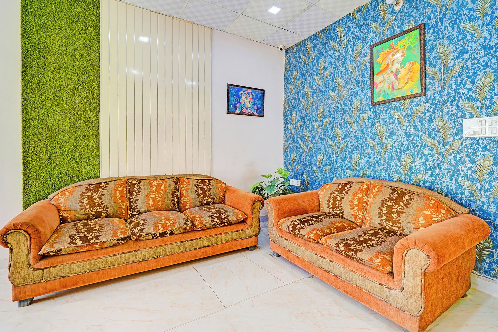 Una habitación con dos sofás, una pared verde vertical y una pared azul con estampado y un cuadro enmarcado.
