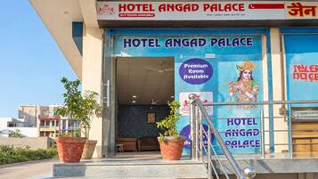 La entrada al Hotel Angad Palace, con un cartel que indica habitaciones disponibles las 24 horas y una opción de habitación premium.