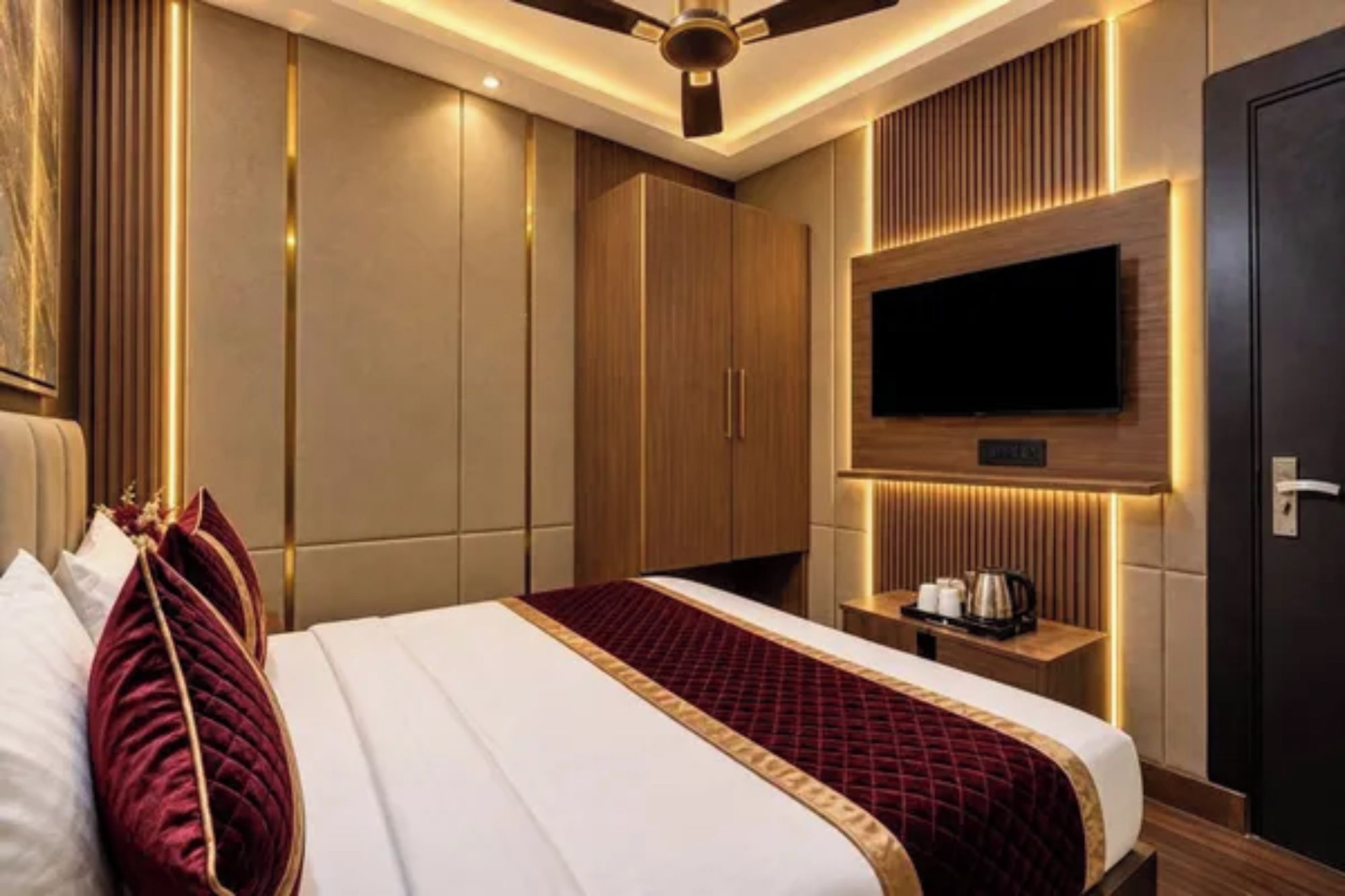Une chambre d’hôtel avec un grand lit, un téléviseur à écran plat fixé au mur et un ventilateur de plafond.