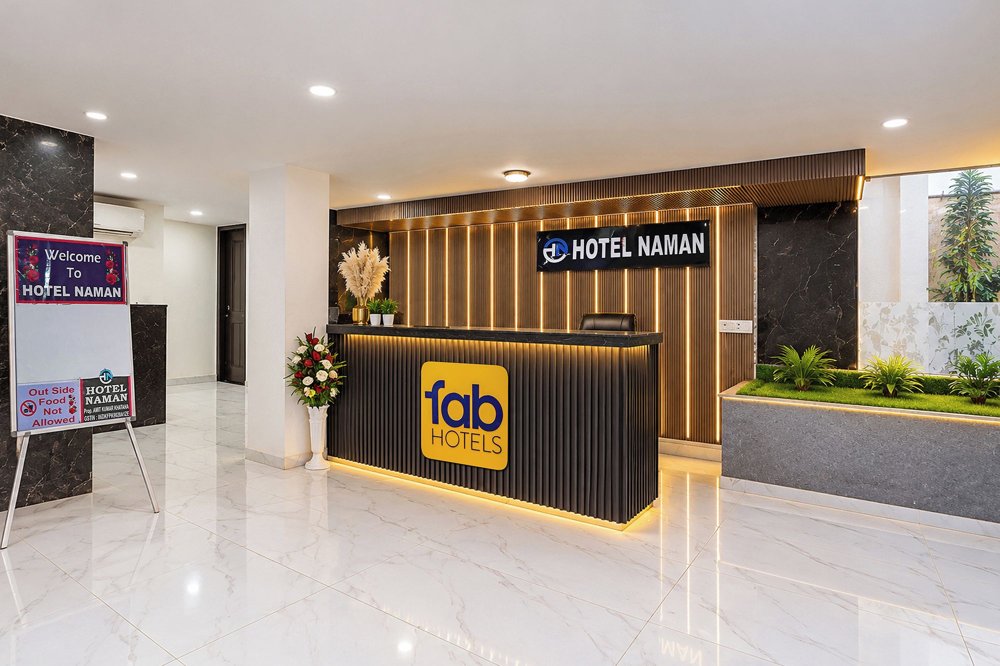 A hotel reception desk with a sign for 'Hotel Naman' and a 'fab hotels' logo.