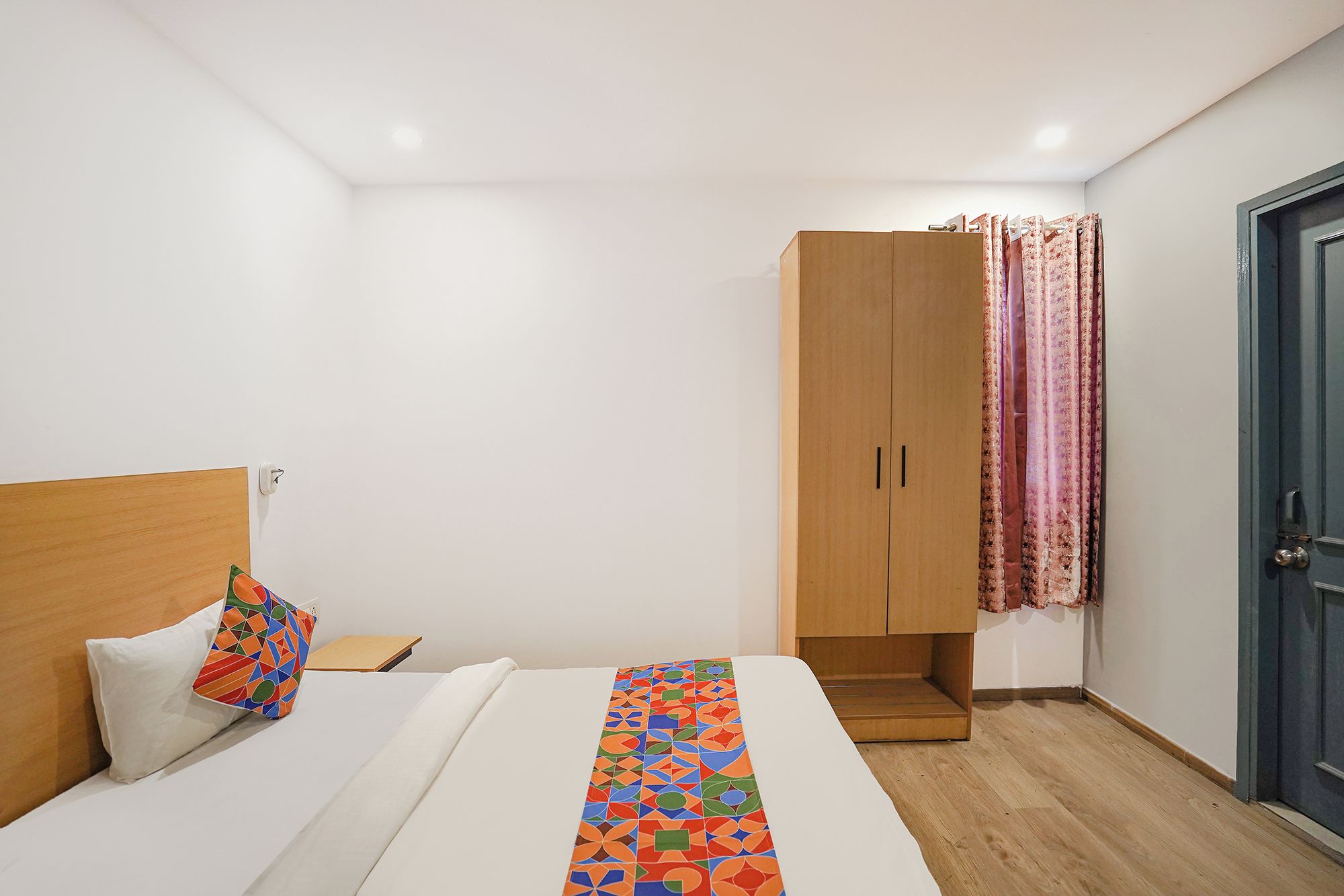 Un dormitorio con una cama, un armario de madera y una puerta con cortinas.