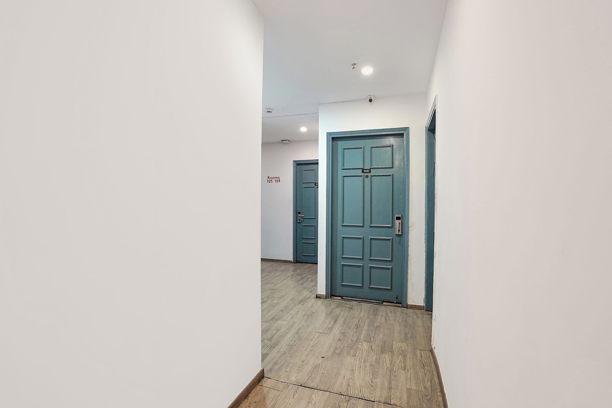 A corridor with doors labeled 'Rooms 105 109' and a blue door with a number plate.