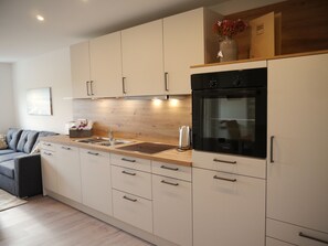 A modern kitchen with a built-in oven, a sink, and a wooden countertop. - A Real Gem - 67 m² Country Apartment for 4 People (Bohmstedt)