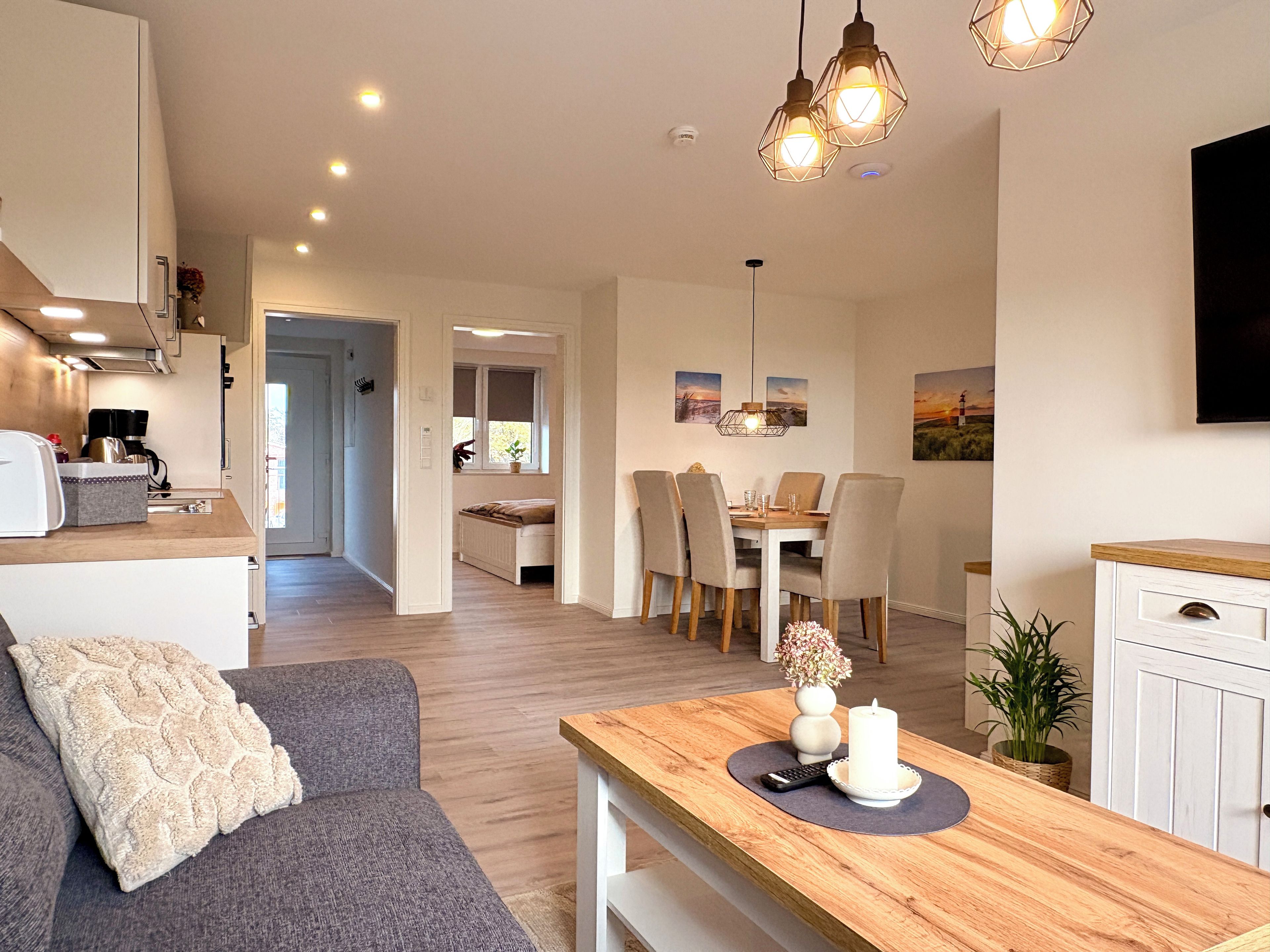A modern living space with a dining area, kitchen, and a sofa.