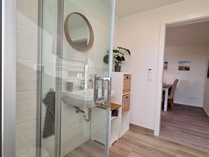A modern bathroom with a glass shower enclosure, a sink, and a mirror. - A Real Gem - 67 m² Country Apartment for 4 People (Bohmstedt)