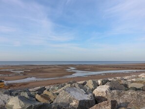 A beach with rocky foreground and a clear sky. - Beach Fields 45 (Rhyl)