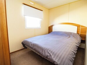 A single bed with a headboard, a window with a blind, and a carpeted floor. - Beach Fields 45 (Rhyl)