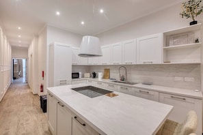 A modern kitchen with white cabinetry, a central island, and a pendant light. - Beautiful Sliema Maisonette w/Patio close to beach (Sliema)