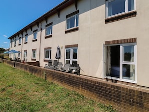A multi-story hotel with a brick facade, multiple windows, and outdoor seating with umbrellas. - Willow (Newton Abbot)