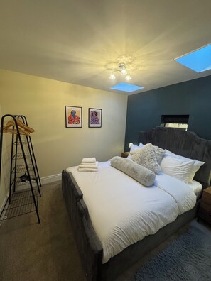 A bedroom with a bed, a nightstand, a wall-mounted shelf, and two framed pictures. - Orchard Cottage- Countryside Retreat by the Peaks (Edlaston)