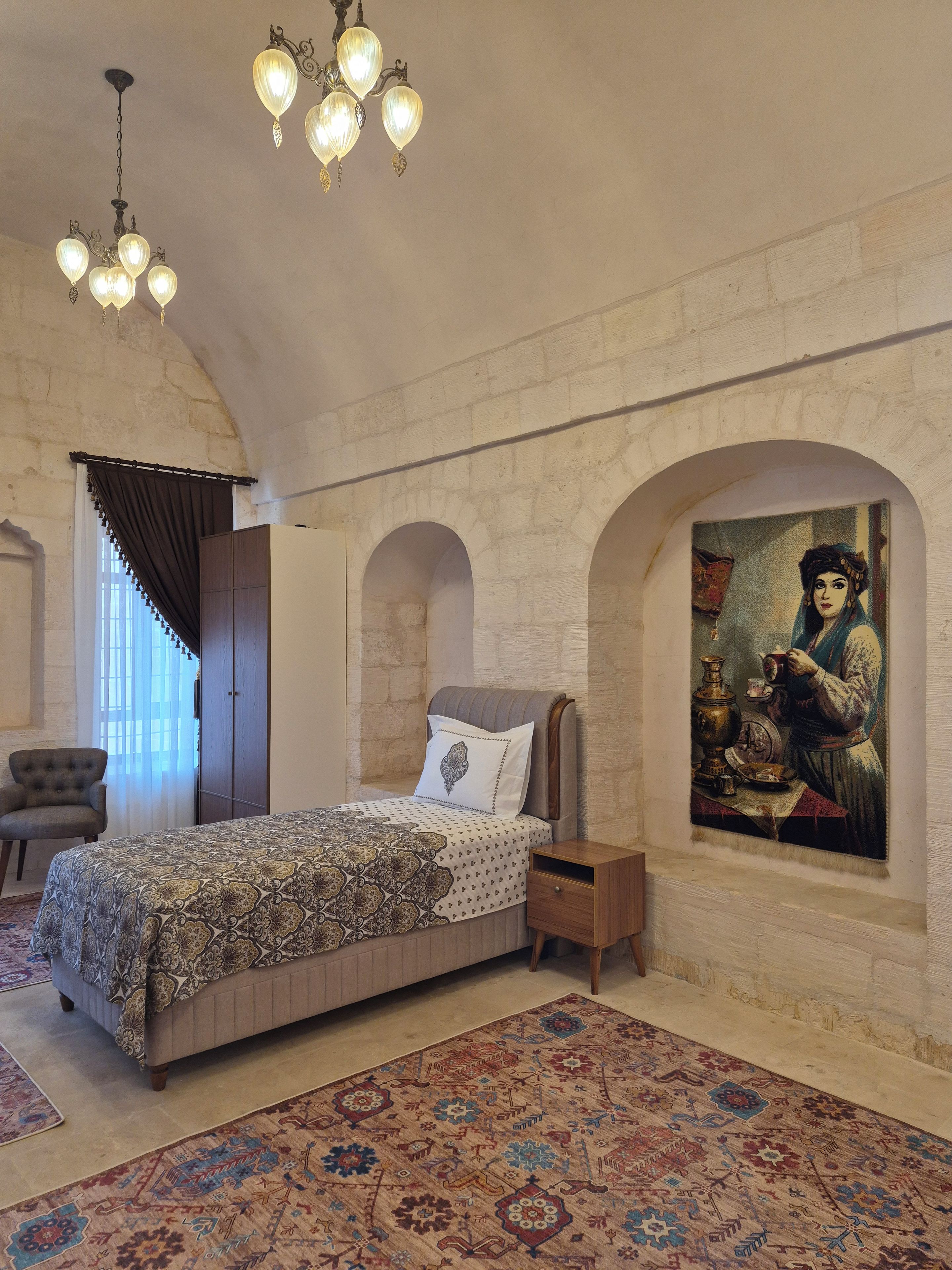 Une chambre à coucher avec un lit, une table de chevet, une chaise, un tapis et un tableau accroché au mur.