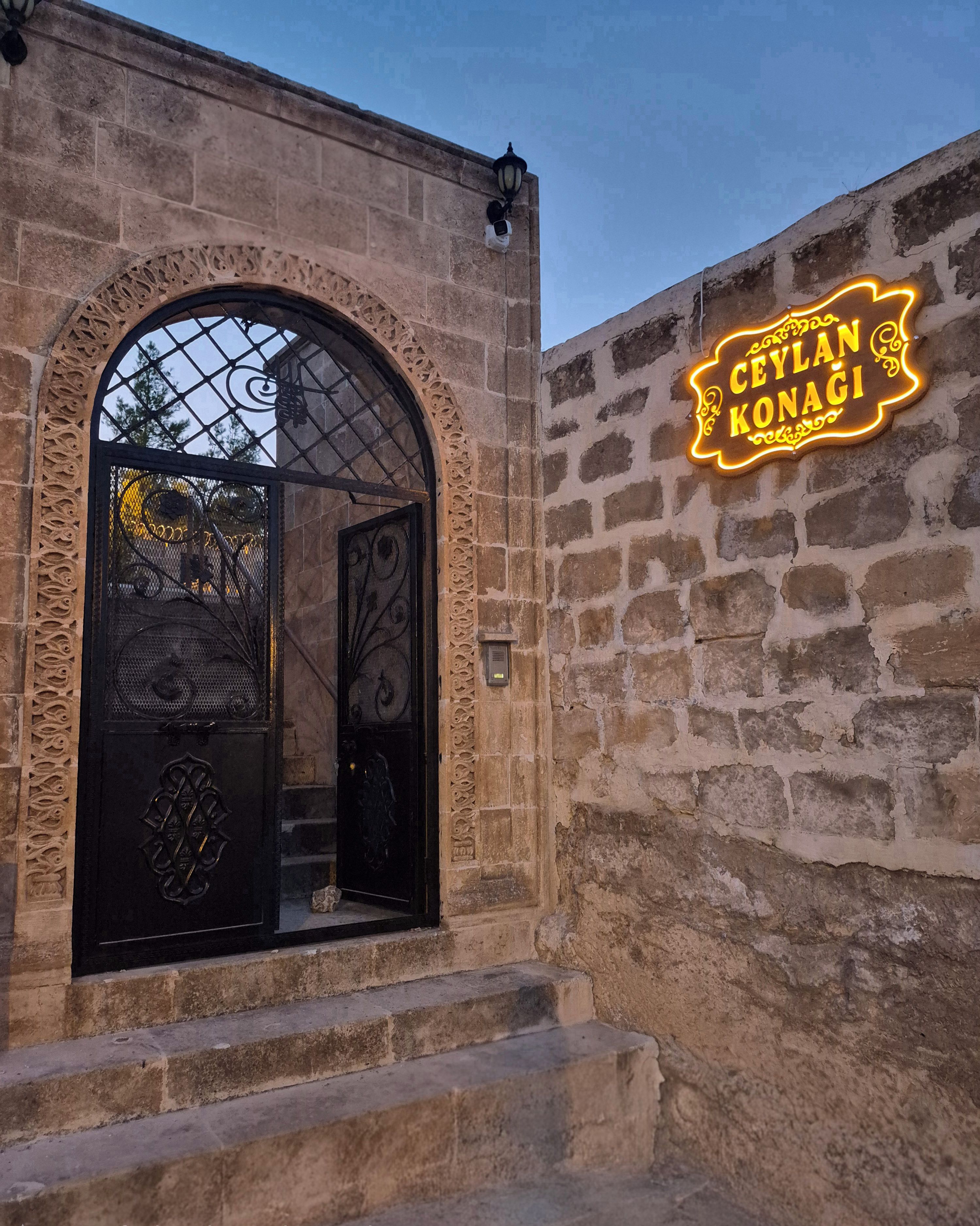 Ein Steinhaus mit einem großen Bogenportal und einem Neonzeichen mit der Aufschrift 'CEYLAN KONAGI'.