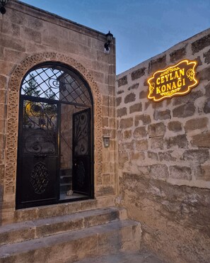 Ein Steinhaus mit einem großen Bogenportal und einem Neonzeichen mit der Aufschrift 'CEYLAN KONAGI'.