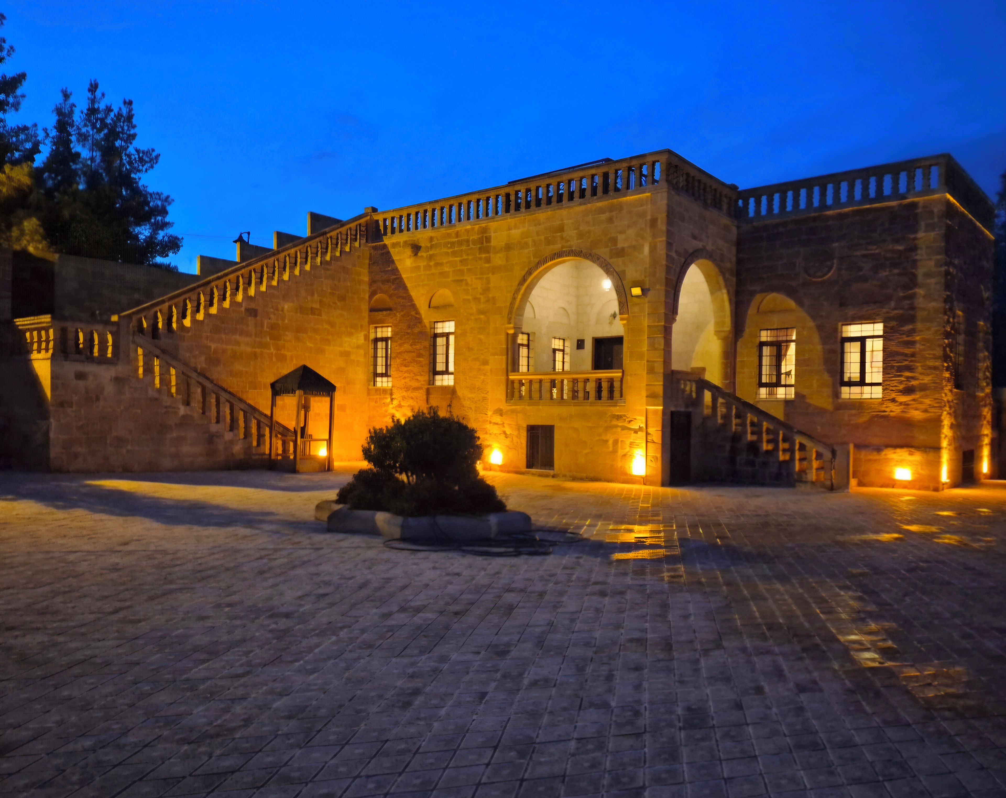 Un edificio histórico con un patio, muros de piedra y ventanas de arco.