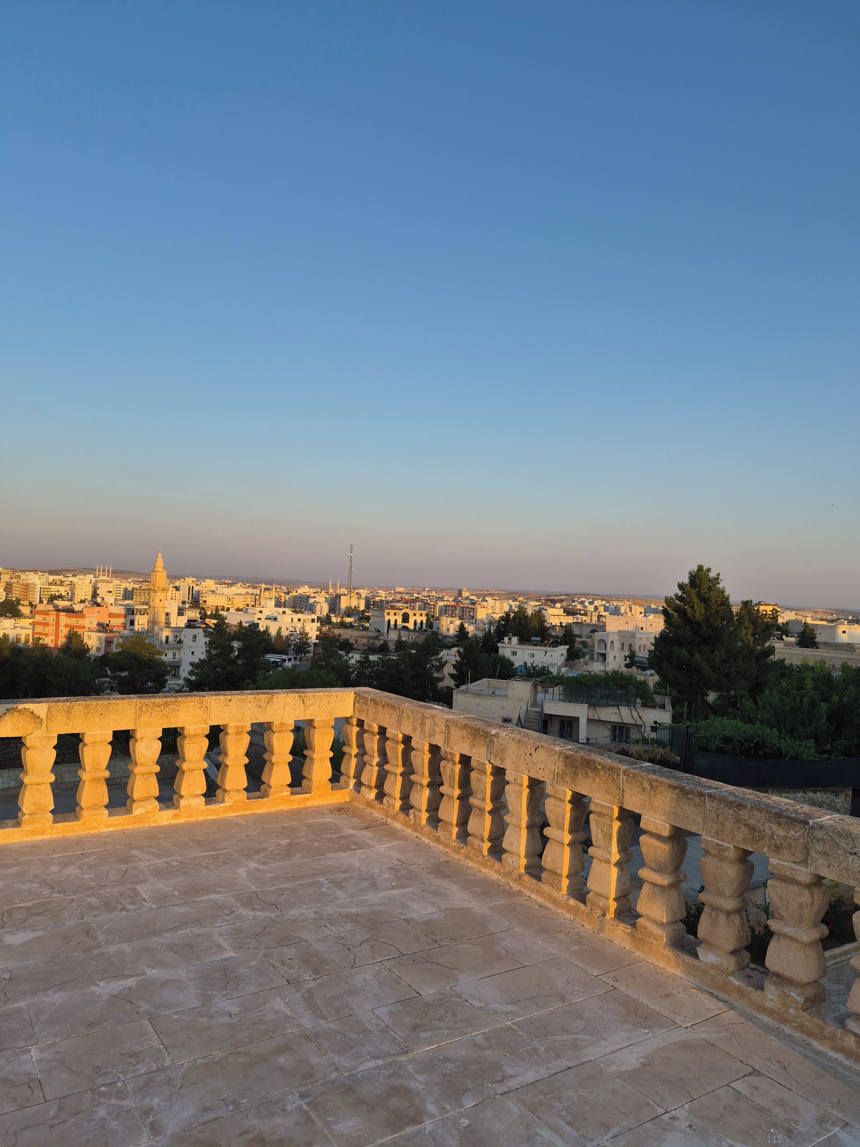 Un balcon en pierre offrant une vue sur le paysage urbain au crépuscule.