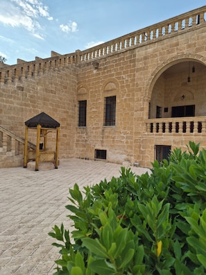 Un patio con muros de piedra, un pabellón de madera y ventanas arqueadas.
