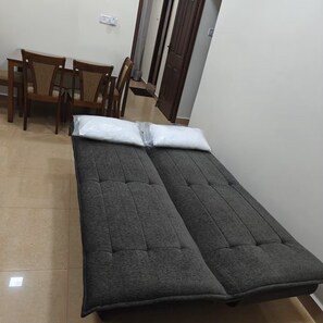 A single bed with a grey mattress and white pillow in a room with a tiled floor and wooden furniture. - Maison Peach.  2BHK near Apollo, Sankara Nethralaya in the Heart of the city! (Chennai)