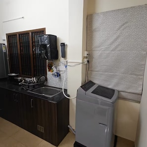A kitchen with a built-in stove, a sink, and a refrigerator. - Maison Peach.  2BHK near Apollo, Sankara Nethralaya in the Heart of the city! (Chennai)