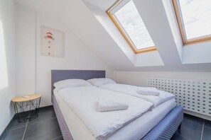 A bedroom with a bed, a small table, and a radiator. - Deluxe Riverside Duplex in the Heart of the City (Prague)