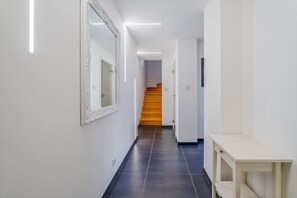 A hallway with a mirror, a staircase, and a small table. - Deluxe Riverside Duplex in the Heart of the City (Prague)