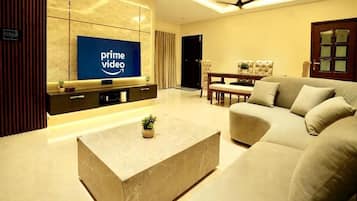 Una sala de estar moderna con un televisor de pantalla plana, un sofá, una mesa de centro y una zona de comedor.