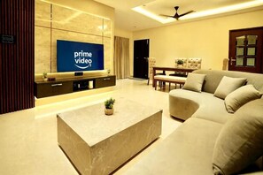Una sala de estar moderna con un televisor de pantalla plana, un sofá, una mesa de centro y una zona de comedor.