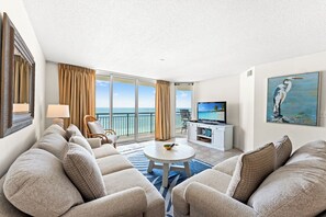 A hotel room with a balcony, a sofa set, a television, and a painting. - Oceanfront Windy Hill Beach 1K 3Q (North Myrtle Beach)
