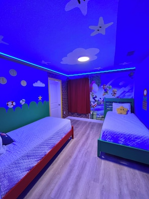 A room with two beds, a door, and a wall with cartoon characters. - PROMO 5 BR Villa | Games | Pool | Near Disney - by Blue Sky Villas (Davenport)