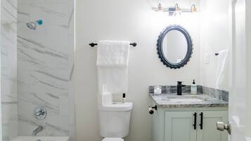 Un baño con ducha, inodoro, lavamanos y espejo.