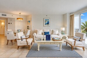 A modern living room with a sofa set, armchairs, a coffee table, and a view of the outdoors. - 3229 Villamare | Beach Access + Incredible Resort Pools (Hilton Head Island)