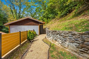 Ein Holzschuppen mit einer Steinmauer und einem Kiesweg, der dorthin führt.