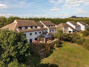 A residential area with multiple houses, a wooden deck with outdoor seating, and a grassy yard. - Avocet (Newton Abbot)