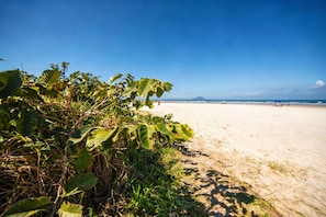 A beach with clear skies, a sandy shore, and some vegetation. - House in Morada da Praia Condominium with WiFi (Bertioga)