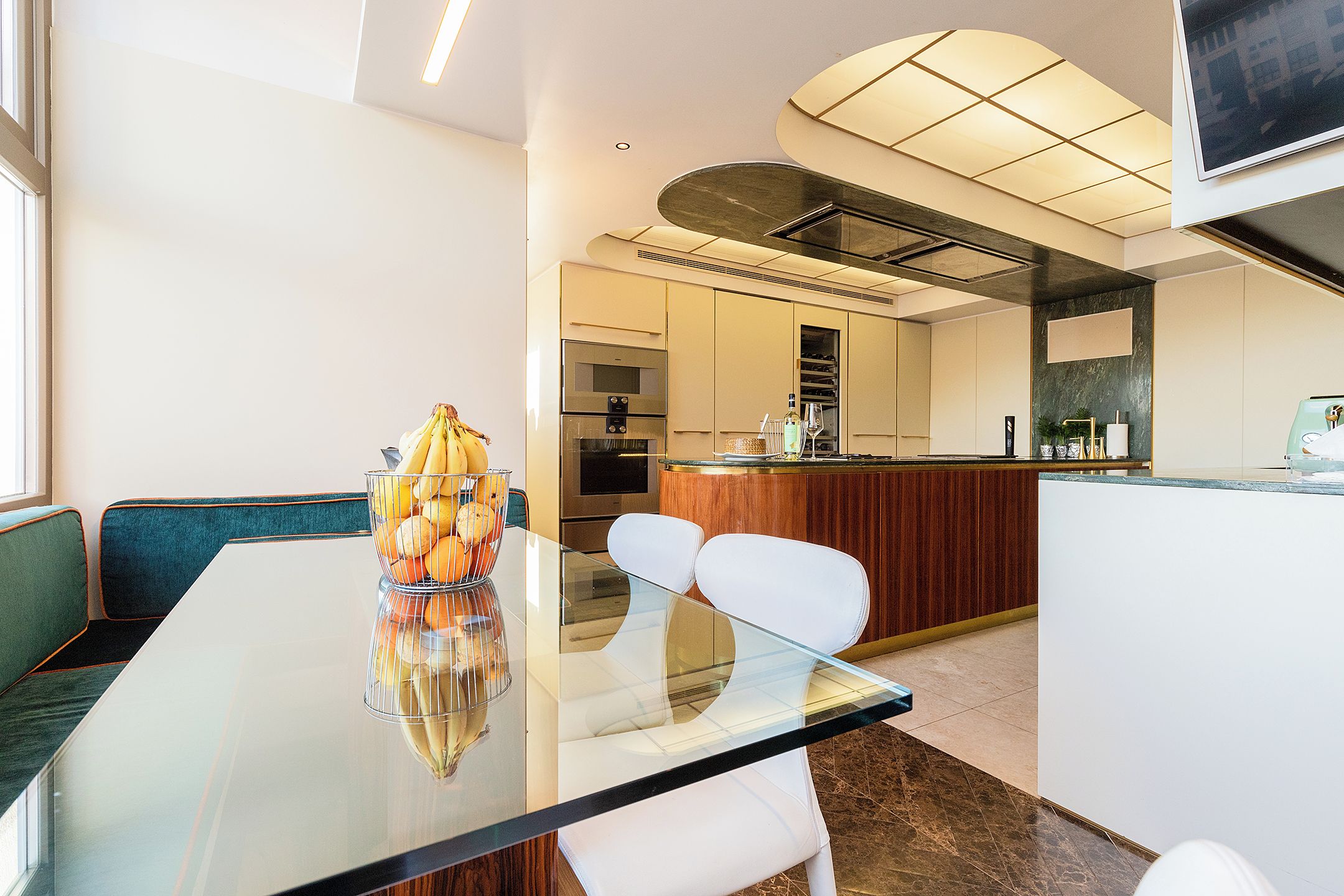 Eine moderne Küche mit Edelstahlgeräten, einer Holztheke und einem Glastisch mit Stühlen.