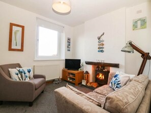 A cozy living room with a fireplace, a television, and a comfortable sofa. - Derwen-las (Penmaenmawr)