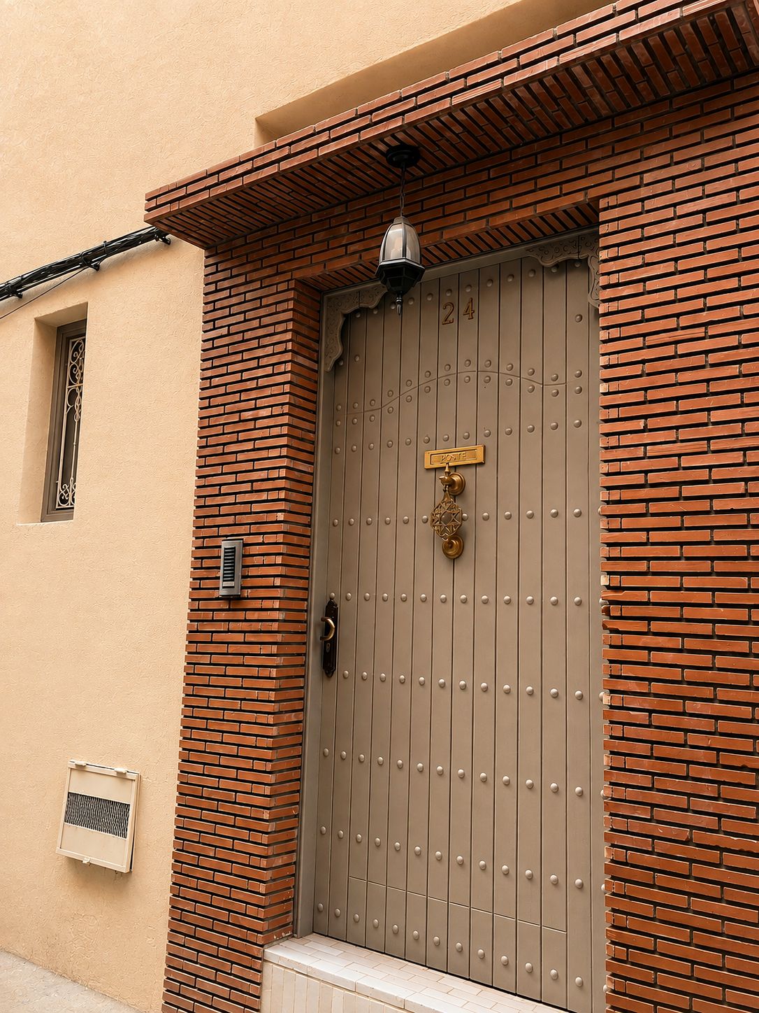 Una puerta de metal marrón con un aldabón de latón y una pequeña placa encima.
