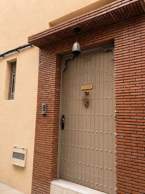 A brown metal door with a brass knocker and a small sign above it. - Riad privé MASKAT (Marrakech)