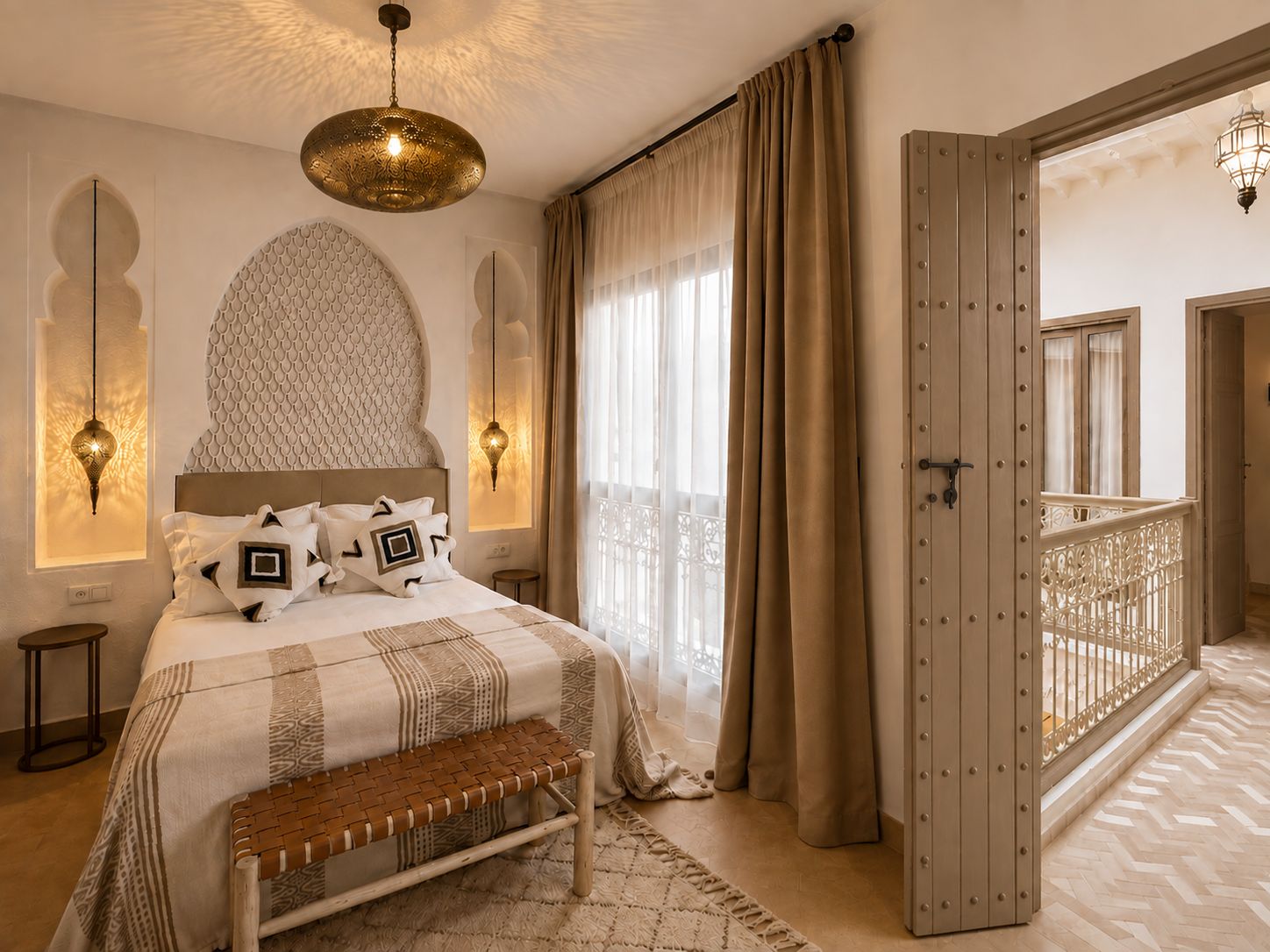 Een slaapkamer met een groot bed, een bankje, een hanglamp en uitzicht op een balkon.