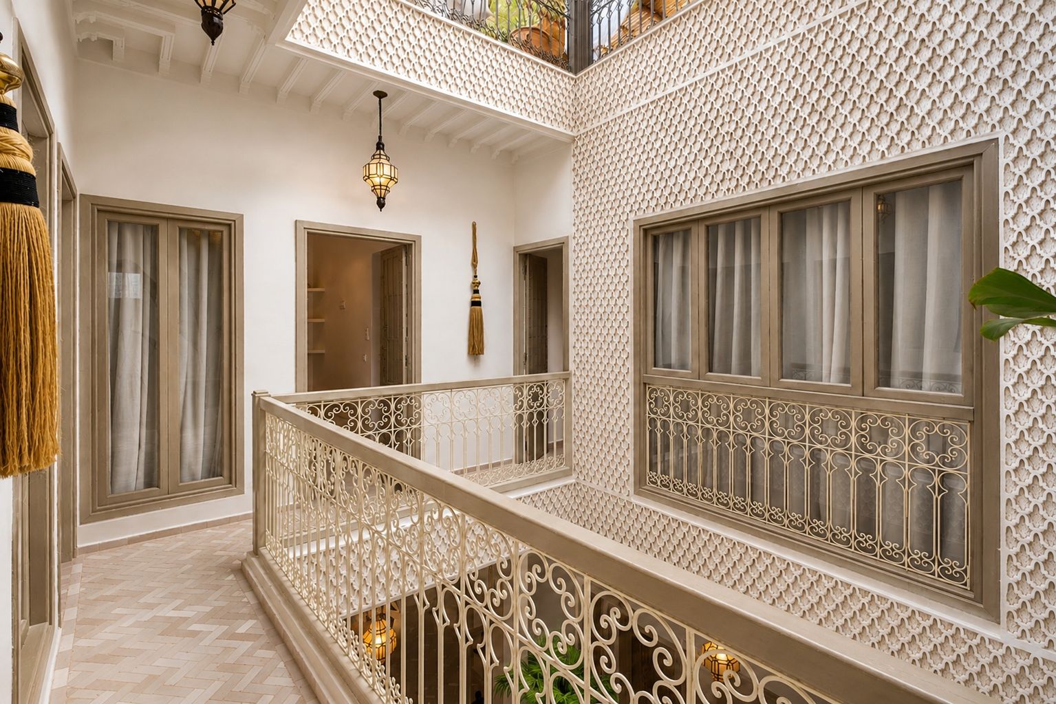 Un interior con varios niveles, barandillas ornamentales, paredes con diseños y suelo en espiga.