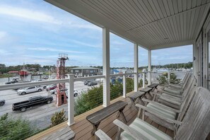A covered outdoor seating area with wooden benches and a view of a marina with boats and a red crane. - Beautiful home super close to the beach!  223 Grey Plover (Lewes)