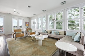A spacious living room with a large window, a sofa, a coffee table, and a chair. - Beautiful home super close to the beach!  223 Grey Plover (Lewes)