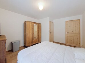 A bedroom with a large bed, wooden wardrobe, and a door. - Chalet des Filles -  7/9 peoples (Saint-Jean-d´Aulps)