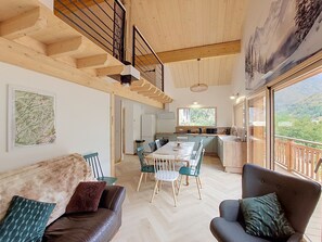 A spacious living area with a high ceiling, a dining table with chairs, a sofa, and a balcony with a view of the outdoors. - Chalet des Filles -  7/9 peoples (Saint-Jean-d´Aulps)