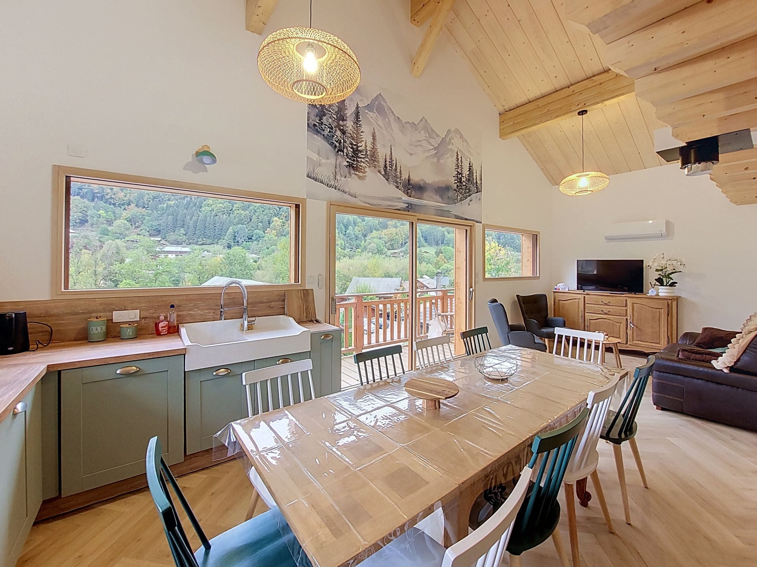 Una cocina moderna con un ventanal amplio, techo de madera y un comedor con sillas y una mesa.
